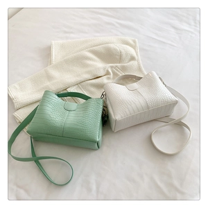 Détail de sacs fourre-tout à motif crocodile vert menthe et blanc sur fond de tissu