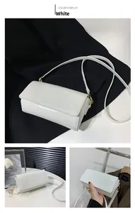 Close-up of white crocodile pattern faux leather baguette bag with gold metal buckle