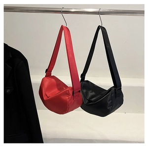 Detail of minimalist crescent nylon crossbody bags in red and black with wide straps