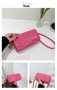 Detail of pink faux crocodile leather baguette bag with golden metal hardware and flap