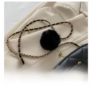 Macro detail of black quilted leather bag with golden camellia buckle and fur charm