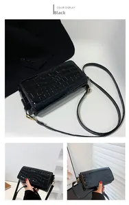 Detail of black crocodile pattern baguette bag featuring gold-tone hardware and texture