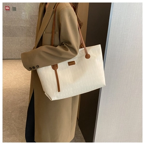 Detail of quilted beige tote bag with brown straps and logo on casual long coat