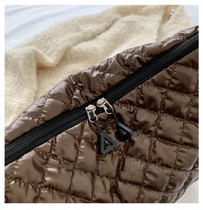 Detail of smooth double zippers and brown quilted satin fabric on large tote bag