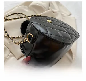 Detail of black quilted leather stitching and chain strap on a round crossbody bag