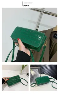 Detail of green crocodile embossed baguette bag with glossy finish and gold hardware