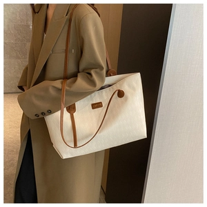 Detail of white oversized tote bag showing woven texture and elegant brown shoulder strap