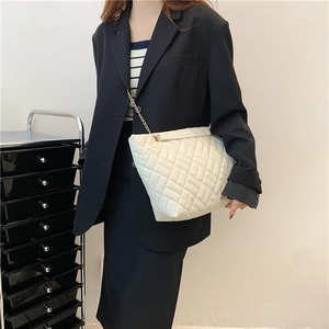 Grande borsa shopping beige trapuntata con tracolla a catena dorata indossata da modella