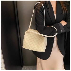 Sac fourre-tout beige à damier porté avec un blazer noir chic et une jupe en satin