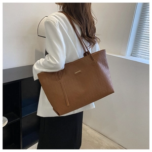 Detail of the embossed diamond pattern on the brown leather tote bag with brand plaque