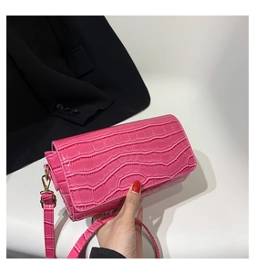 Close-up of bright pink faux leather baguette bag with premium crocodile texture