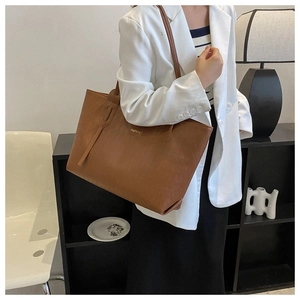 Detailed close-up of brown woven texture tote bag with elegant golden logo emblem
