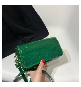 Close-up of green crocodile embossed baguette bag with glossy texture and gold buckle