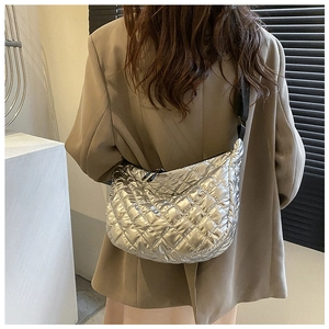 Detailed view of silver quilted dumpling bag with metallic finish and wide strap