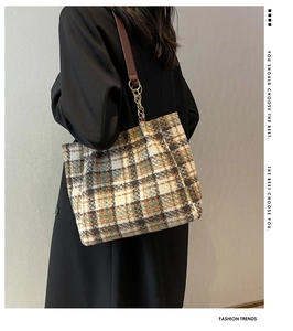 Détail d'un sac cabas à carreaux marron avec lanières en cuir et chaînes dorées