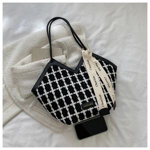 Detail of black and white tweed tote bag with elegant bow ribbon and logo label