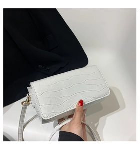 Detail of white baguette bag featuring crocodile pattern texture and gold hardware