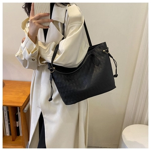 Close-up of black quilted tote bag with gold hardware and side drawstring detail