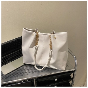 Détail de cabas blanc en cuir souple avec chaînes dorées dans un bureau moderne