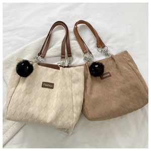 Detail of cream and camel quilted tote bags with plush charm and fashion patch