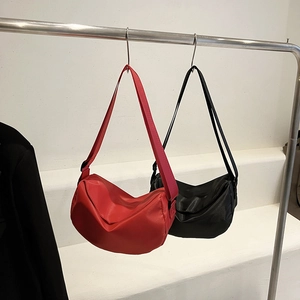 Minimalist nylon crescent shoulder bags in classic black and bright red hanging on a rack