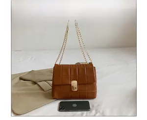 Quilted caramel shoulder bag detail with gold chain strap and phone for scale
