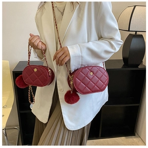 Close-up of wine red quilted oval bag with gold flower buckle and chain strap