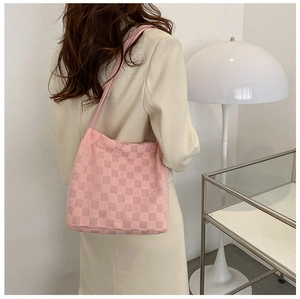 Détail d'un sac cabas en peluche à damier rose porté à l'épaule sur un mannequin