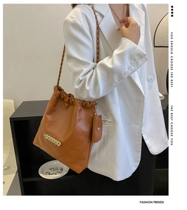 Close-up of brown quilted bucket bag with gold chain strap and matching coin purse