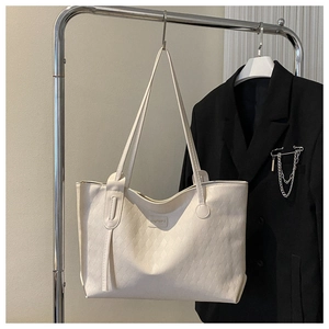 Close-up of cream white tote bag with diamond quilted pattern and shoulder straps