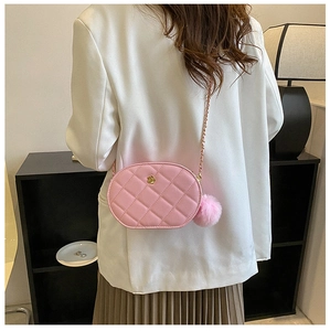 Detailed view of pink quilted oval bag with gold flower clasp and plush pompom charm