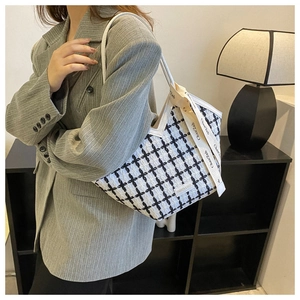 Detail of checkered tote bag with fashion tag and ribbon handle on a shoulder strap