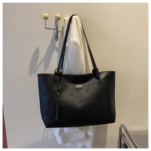 Detailed view of black tote bag with quilted diamond texture and shoulder strap