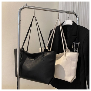 Detail showing quilted texture and slim straps of black and off-white tote bags