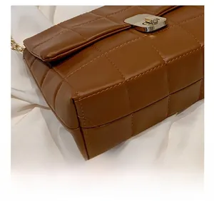 Detail of brown quilted chain bag showing precision stitching and gold metal lock closure