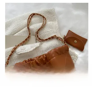 Detailed view of brown quilted tote bag with golden metal chain strap and coin purse