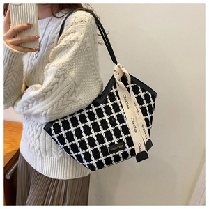 Close-up of black and white plaid tweed tote bag with ribbon and fashion leather patch