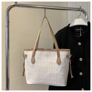 Detail view of large white quilted tote bag with rhombus pattern and beige slim shoulder straps