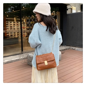 Outdoor lifestyle shot of a brown quilted chain bag worn by a model in a mohair sweater