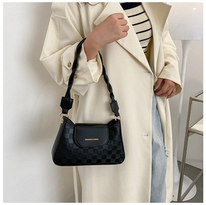 Detail of black crossbody bag with checkered texture and twisted woven shoulder strap