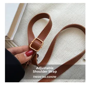 Detail of adjustable brown leather strap with a square golden metal buckle