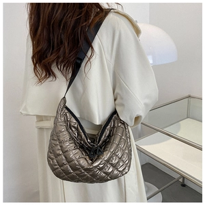 Gros plan sur le sac fourre-tout matelassé doré avec bandoulière noire et surpiqûres