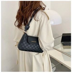 Close-up of black crossbody bag featuring checkered texture and gold buckle detail