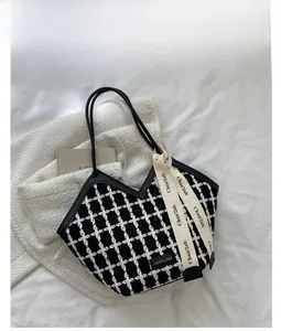 Detail of tweed checkered tote bag with fashion ribbon and black long handles