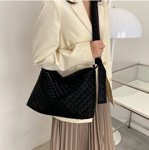 Detail of black quilted shoulder bag featuring premium texture and padded wide strap