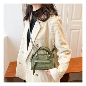 Dettaglio borsa vintage verde scuro in pelle con nappa e cerniera frontale decorativa