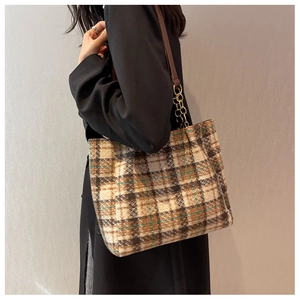 Détail du sac cabas à carreaux avec lanières en cuir marron et accents de chaîne dorée