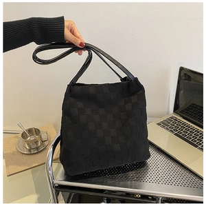 Détail du sac cabas tissé à damier noir présenté dans un décor de bureau élégant