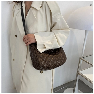 Gros plan d'un sac bandoulière matelassé marron foncé avec large sangle noire