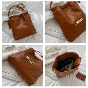 Macro shot of caramel brown quilted leather bucket bag details with gold chain strap